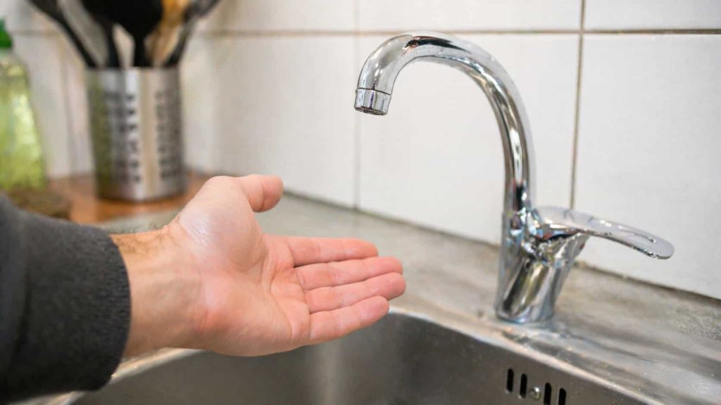 Un homme se lave les mains au robinet